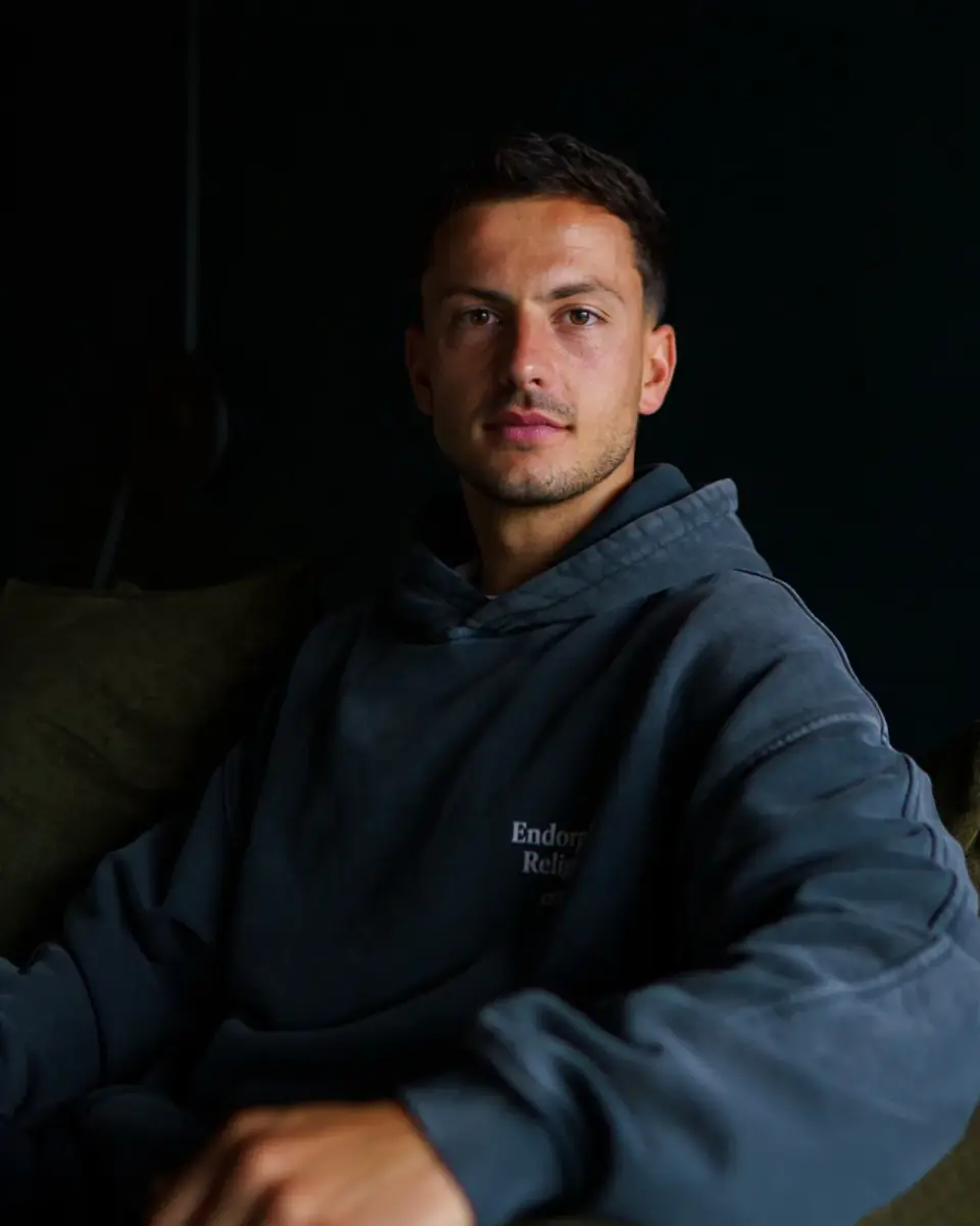 Portrait de Mathieu Valdher, préparateur mental, assis dans un intérieur sombre devant son ordinateur.